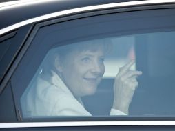 Angela Merkel saluda desde su auto cuando llega a las festividades a la reunificación de la marca de Alemania. AFP  /