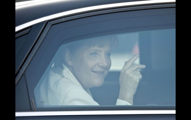 Angela Merkel saluda desde su auto cuando llega a las festividades a la reunificación de la marca de Alemania. AFP  /