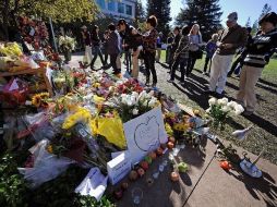 Seguidores de Jobs observan las flores y recuerdos dejados en su memoria en las oficinas centrales de Apple. AFP  /