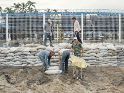 Trabajadores colocan los costales para resguardar el Estadio de voleibol. EFE  /