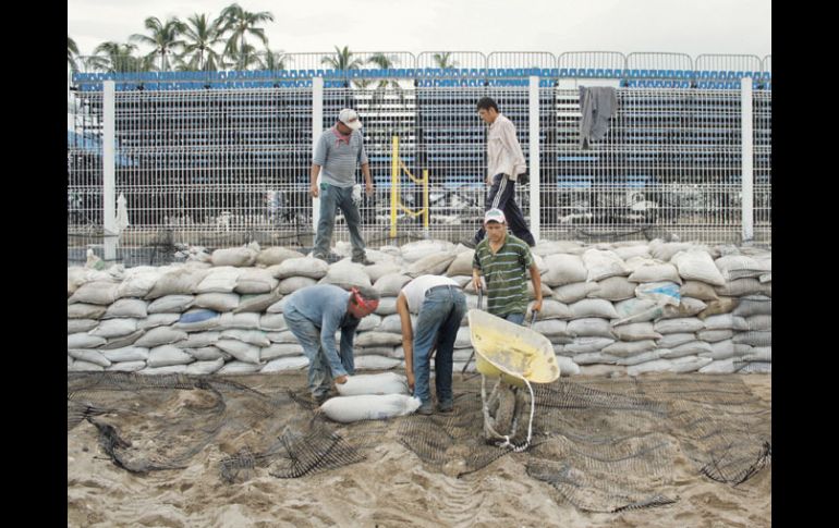 Trabajadores colocan los costales para resguardar el Estadio de voleibol. EFE  /