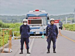 Dos policías japoneses hacen guardia en un puesto de control de entrada a los 20 km de área restringida. EFE  /