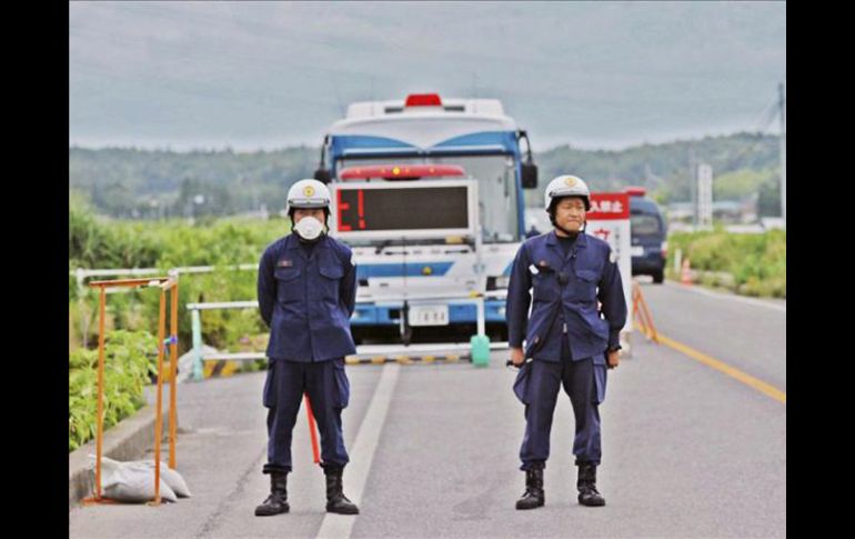 Dos policías japoneses hacen guardia en un puesto de control de entrada a los 20 km de área restringida. EFE  /