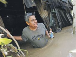 Daniel Martínez recupera una imagen del Santo Niño de Atocha, en su casa inundada. AP  /