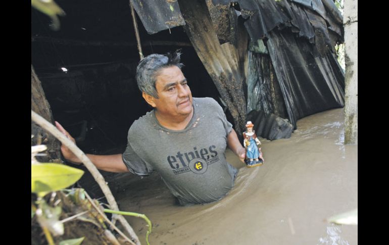 Daniel Martínez recupera una imagen del Santo Niño de Atocha, en su casa inundada. AP  /