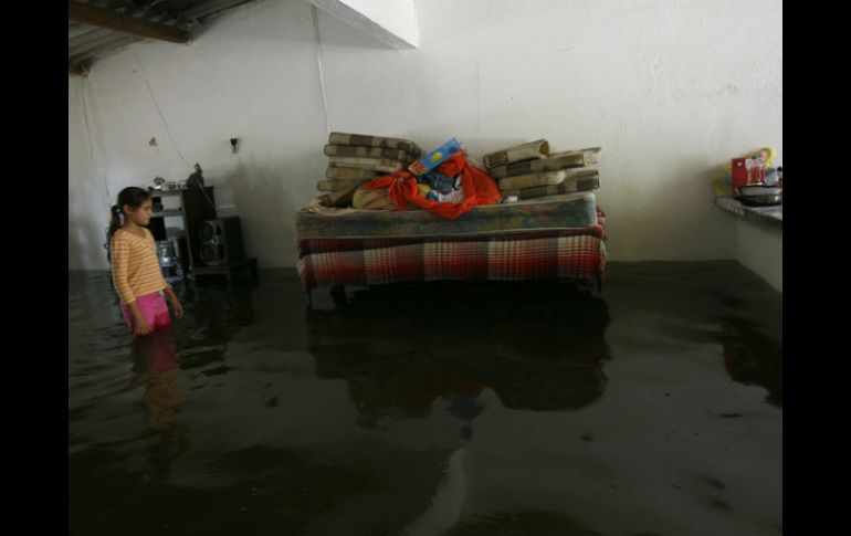 Iris Villa observa flotar sus pertenencias en su casa en El Chavarín, Colima. AP  /