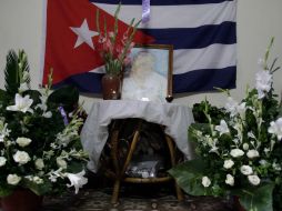 Una pintura de Laura Pollán, líder del grupo disidente Damas de Blanco, está flanqueada por flores, velas y una bandera cubana. AP  /