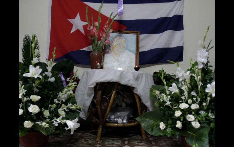 Una pintura de Laura Pollán, líder del grupo disidente Damas de Blanco, está flanqueada por flores, velas y una bandera cubana. AP  /