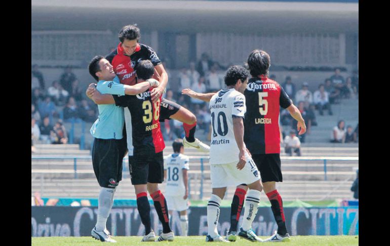 Jugadores del Atlas se abrazan festejando el triunfo sobre Pumas, ayer a mediodía en el Estadio Olímpico Universitario. MEXSPORT  /