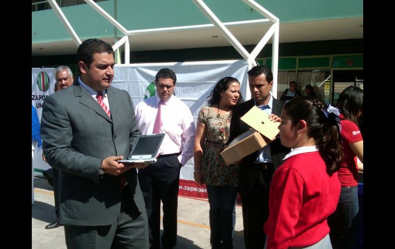 El alcalde de Zapopan, Héctor Vielma, hace entrega de una computadora a una estudiante.  /