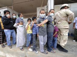 Niños hacen fila para entrar a ver los restos de Gadhafi, llevan cubrebocas debido al mal olor que desprenden los cuerpos. AFP  /