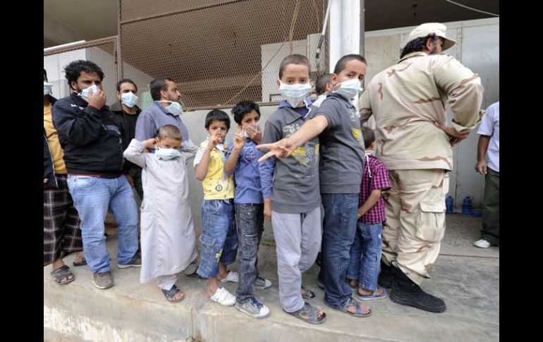 Niños hacen fila para entrar a ver los restos de Gadhafi, llevan cubrebocas debido al mal olor que desprenden los cuerpos. AFP  /