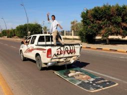 Un libio arrastra simbólicamente un retrato de Gadhafi en Sirte, en la parte posterior del transporte se lee: Alá es grande. REUTERS  /