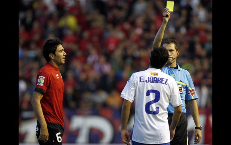 El centrocampista del Osasuna Nekounam, observa al árbitro José Luis González sacar la tarjeta amarilla al mexicano Efraín Juárez. EFE  /