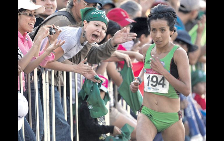 Madaí Pérez es animada por una mujer espectadora durante el recorrido del maratón femenil.  /