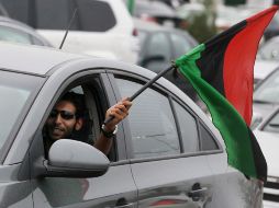 Un hombre ondea la bandera nacional por la ventanilla de su coche mientras celebra la liberación de Libia. EFE  /