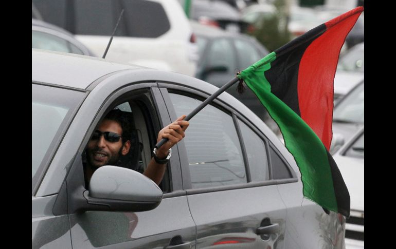 Un hombre ondea la bandera nacional por la ventanilla de su coche mientras celebra la liberación de Libia. EFE  /