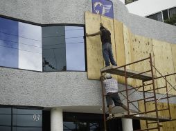 Empleados de una empresa cubren las ventanas del local. AFP  /