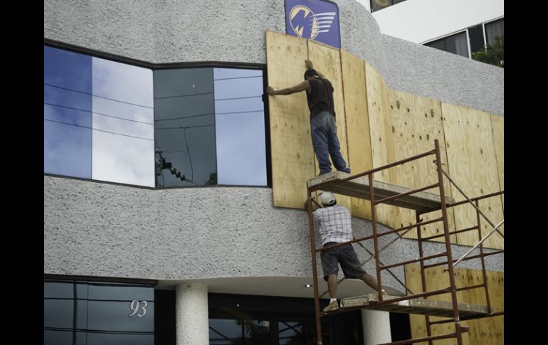 Empleados de una empresa cubren las ventanas del local. AFP  /