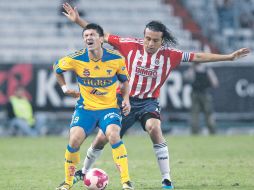 Héctor Reynoso, zaguero de Chivas, llega por atrás y le da un ligero golpe a su tocayo Mancilla, de Tigres. MEXSPORT  /