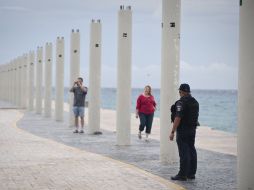 Un policía pide a turistas que se retiren, por su seguridad, en Playa del Carmen. AFP  /