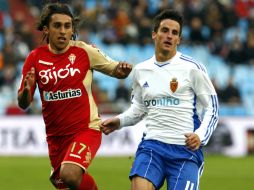 El centrocampista del Zaragoza, Juan Carlos Pérez (d), intenta llegar a la pelota antes que el defensa del Sporting Damián Suárez. EFE  /