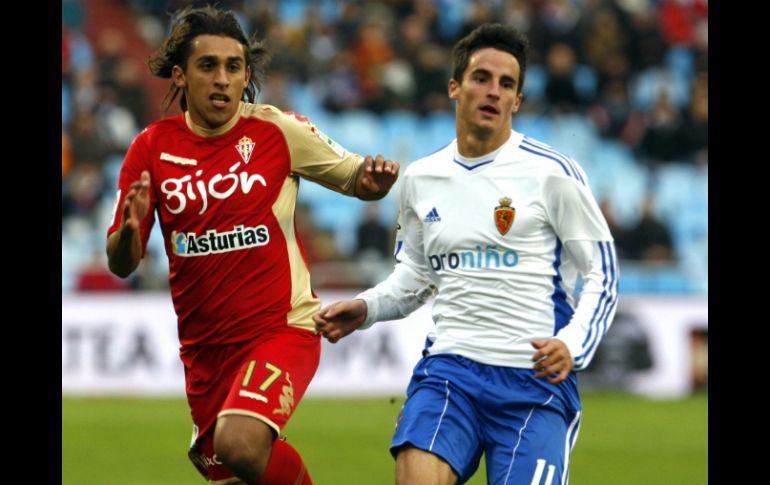 El centrocampista del Zaragoza, Juan Carlos Pérez (d), intenta llegar a la pelota antes que el defensa del Sporting Damián Suárez. EFE  /