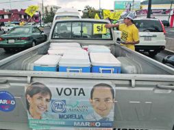 Un militante del PRD pega una calmomanía a favor de su partido en una camioneta que también luce publicidad del PAN. EL UNIVERSAL  /