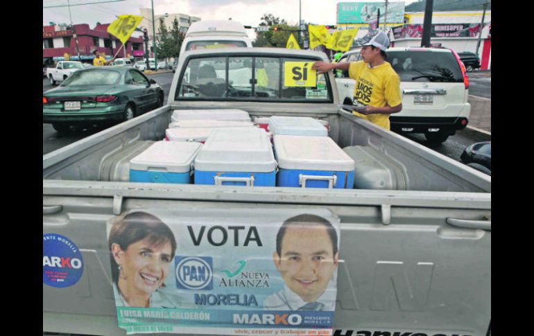 Un militante del PRD pega una calmomanía a favor de su partido en una camioneta que también luce publicidad del PAN. EL UNIVERSAL  /