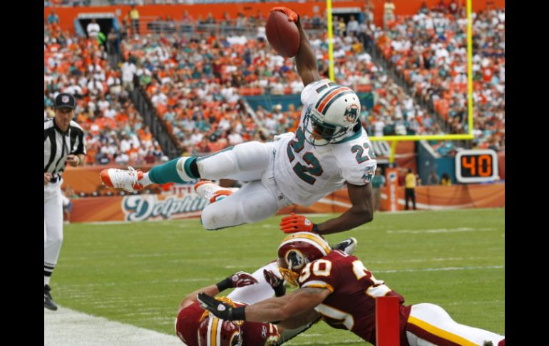 El correor Reggie Bush (22)salta antes de la zona de anotación sobre el defensa de Washington LaRon Landry (30). AP  /