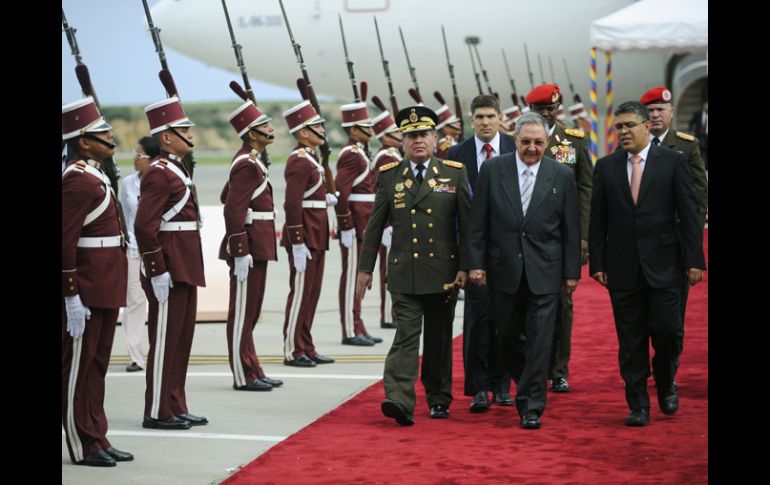 El presidente Raúl Castro (C) es recibido en el aeropuerto de Caracas.  AFP  /