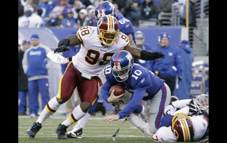 Brian Orakpo (I) salta sobre Eli Manning (C) después de que su compañero Stephen Bowen le capturara, (Abajo- Der). AP  /