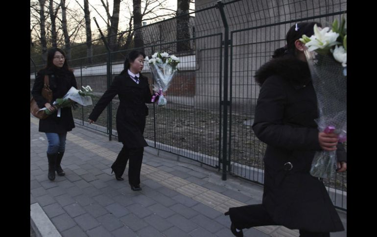 Varias mujeres llevan ramos de flores a la embajada de Corea del Norte en Pekín como muestra de duelo por la muerte del líder. EFE  /