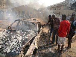 Hombres miran los restos de un cochebomba que explotó cerca de la iglesia de Santa Teresa en la ciudad de Abuja. AFP  /