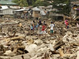 Varios damnificados por las inundaciones caminan entre troncos arrastrados por las aguas. EFE  /