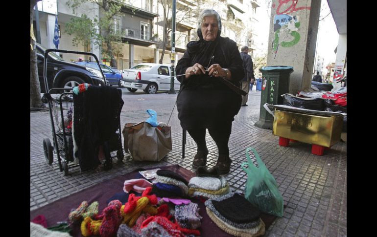 Una mujer teje diversos objetos que después vende en una calle del centro de Atenas, Grecia. EFE  /