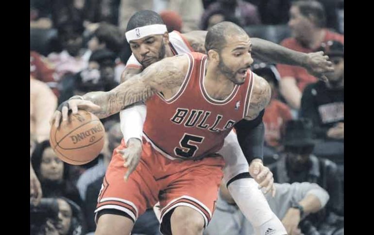 Josh Smith (de blanco), de los Hawks de Atlanta, intenta robarle el balón a Carlos Boozer, de los Bulls de Chicago. AP  /