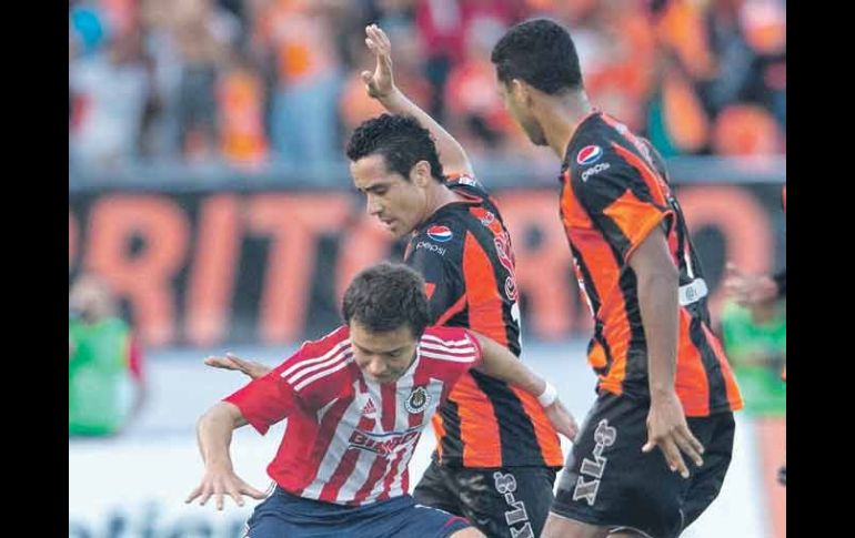 ''Cubo'' Torres, de Chivas, trata de avanzar ante la marca de dos defensas chiapanecos. MEXSPORT  /