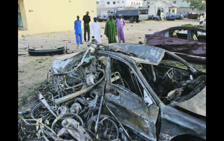 Personas observan coches destruidos en el sitio de un bombardeo suicida en la sede de Policía en Kano, Nigeria. AP  /