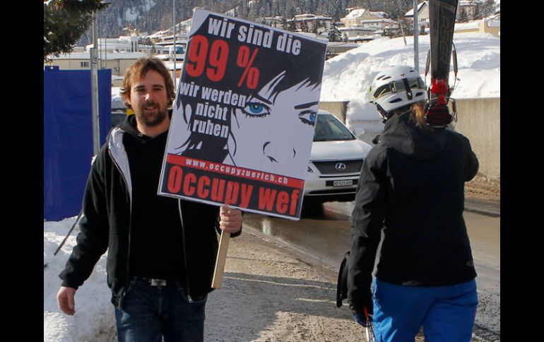 Miembro del movimiento ''Occupy WEF'' sostiene un cartel que dice: somos un 99%, que solía descansar. AP  /