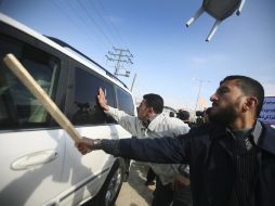 Familiares y amigos de prisioneros palestinos en israel golpean con palos de madera un vehículo del convoy. EFE  /