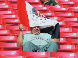 Un aficionado rojiblanco se cubre del sol con su bandera de las Chivas, en uno de los encuentros en el Omnilife.  /