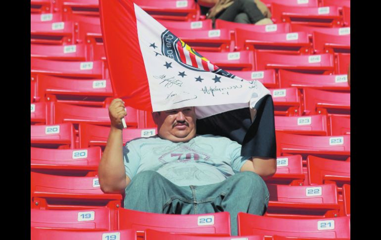 Un aficionado rojiblanco se cubre del sol con su bandera de las Chivas, en uno de los encuentros en el Omnilife.  /