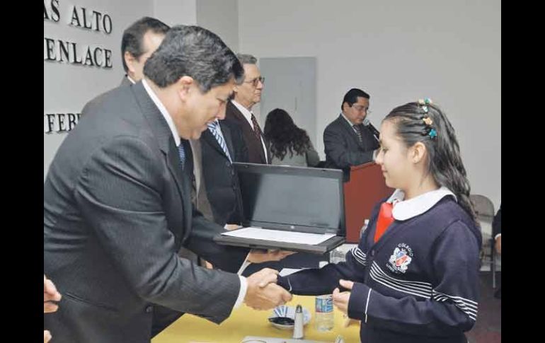 Antonio Gloria Morales entrega una computadora a una de las estudiantes destacadas de la prueba ENLACE.  /