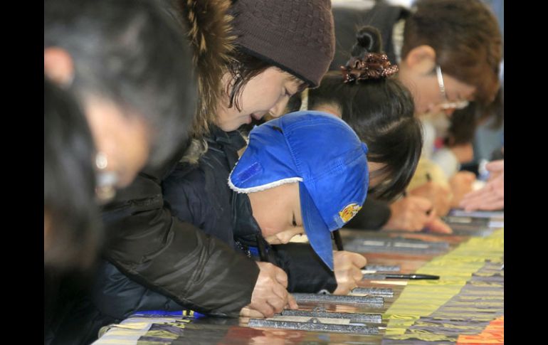 Ciudadanos visitan el palacio imperial japonés para firmar un libro de buenos deseos para que el emperador se mejore.  AP  /