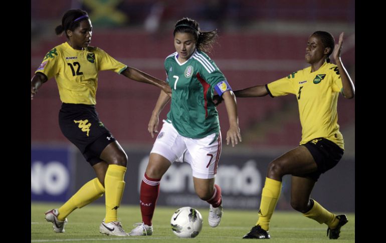 Nayeli Rangel pasa con el balón controlado ante dos jugadoras de Jamaica. AP  /