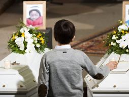 Un niño deja una vela en un ataúd durante el funeral de seis de los niños. EFE  /