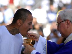 Un miembro de la ''Mara Salvatrucha'' recibe la comunión durante la misa. REUTERS  /