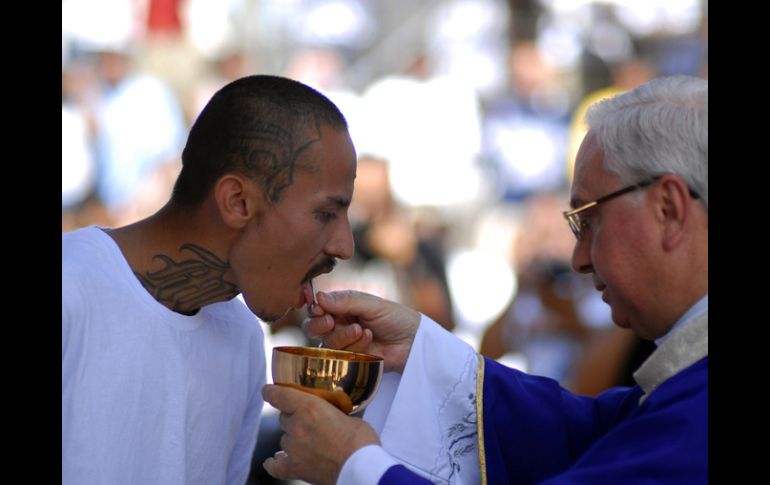 Un miembro de la ''Mara Salvatrucha'' recibe la comunión durante la misa. REUTERS  /