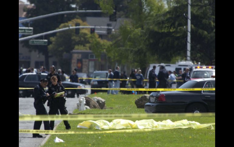 Policías investigan junto a varios cuerpos que permanecen cubiertos en frente de la universidad. EFE  /